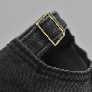 Detailed macro view of the vintage brass adjustment buckle on a washed cotton baseball cap