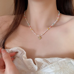 Detailed close-up of a colorful beaded mushroom necklace with gold pendant on a model