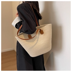 Detailed close-up of a large woven cotton tote bag featuring premium brown leather handles