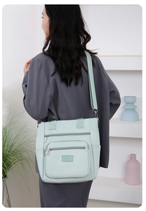 Detail view of mint green multi-pocket nylon shoulder bag with adjustable strap