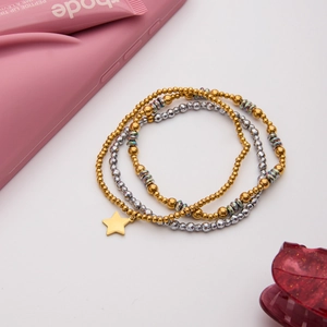 Three-piece layered beaded bracelet with gold beads, silver facets, and star charm