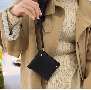 Detailed view of a black pebbled leather wristlet pouch with elegant gold studs