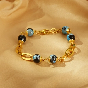 Detail of vintage gold bracelet with marble beads on luxury champagne silk fabric