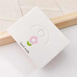 Macro shot of white handmade card tag featuring pink floral print and elegant script