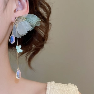 Macro detail of tassel butterfly earrings with light green wings and crystal drops