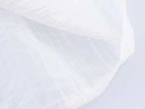Close-up of premium white cotton fabric texture with delicate lace stitching details