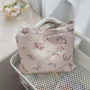 Close-up of butterfly embroidery detail on floral jacquard fabric shoulder bag