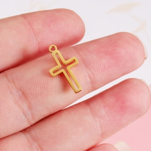 Polished gold hollow cross pendant held between fingers showing its compact size