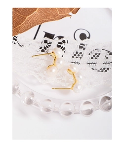 Détail de boucles d'oreilles en argent S925 doré avec trois perles blanches élégantes