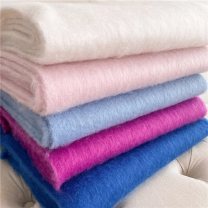 Gros plan d'écharpes en mohair doux de plusieurs couleurs empilées sur un canapé