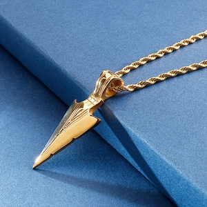 Close-up of golden arrowhead pendant with intricate textures on a twisted rope chain
