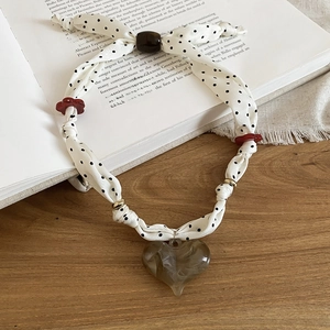 Polka dot fabric necklace featuring a marble grey resin heart pendant on a book