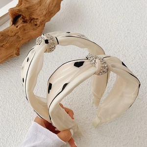 Detail of beige satin headband with black polka dots and sparkling rhinestone knot decoration