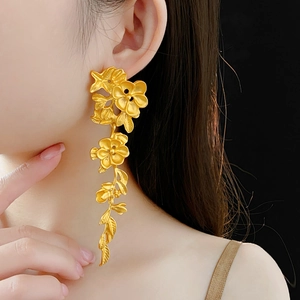 Vue détaillée de boucles d'oreilles fleurs dorées avec pétales et feuilles à texture mate