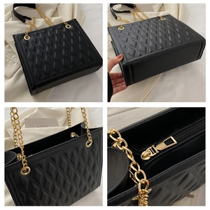 Detail view of black quilted tote bag with gold chain strap and interior zip pocket