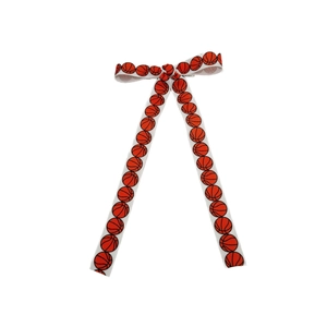 Detail of white ribbed ribbon hair bow with festive red basketball pattern print