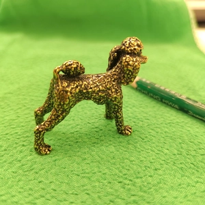 Detailed close-up of a miniature bronze poodle figurine with fine textured curly fur details
