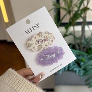 Floral and marble cloud-shaped hair clips with Fancy lettering on a display card