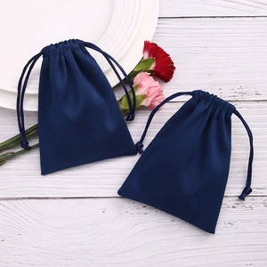 Dark blue flannel jewelry pouches with drawstrings on a minimalist wooden background