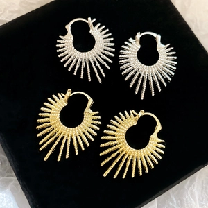 Detailed sunburst texture earrings in gold and silver finish on black velvet display