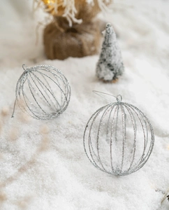 Close-up of silver hollow Christmas ornaments with glitter finish on a snowy background