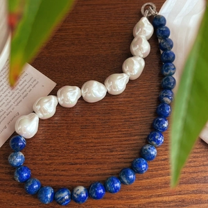 Detail of baroque pearls and lapis lazuli beads necklace on a vintage wood surface