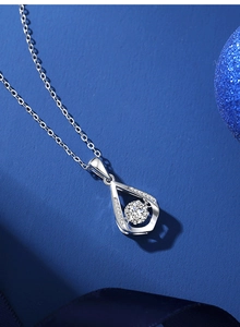 Macro shot of silver water drop pendant with a bright center stone on a blue background
