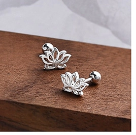 Macro shot of silver lotus stud earrings with spherical screw backs on a wood background