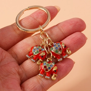 Detail eines goldenen Schlüsselanhängers mit drei roten Emaille-Elefanten und Strass