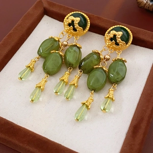 Macro shot of vintage gold earrings with olive green jade pendants and fringe details