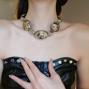 Detailed view of irregular polished silver metal beads on a necklace worn by a model