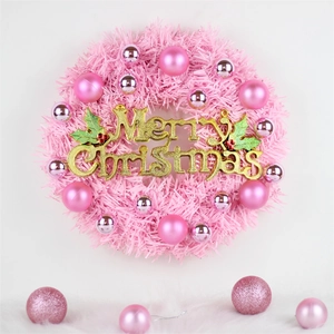 Pink Christmas wreath with ornaments and golden Merry Christmas sign on white background