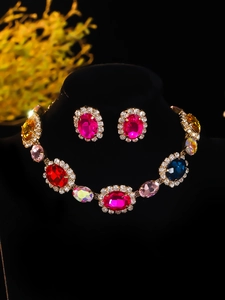 Detail view of multicolored gemstone necklace and earrings set on golden alloy base
