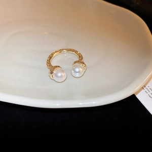 Detail of gold hammered ring with dual white pearls on a minimalist ceramic plate