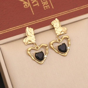 Gros plan de boucles d'oreilles cœur en or à texture lave avec pierre noire et zircon
