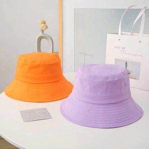 Detail view of cotton bucket hats in vibrant orange and lilac with parallel brim stitching