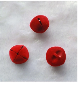 Three red flocked Christmas bell ornaments on white plush background for DIY wreaths