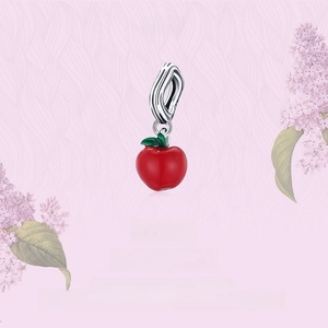 Macro detail of red apple charm with green leaf in S925 silver on floral background