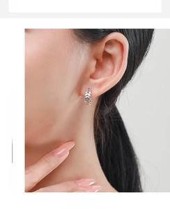 Detailed close-up of 925 sterling silver leaf hoop earrings worn on model's ear