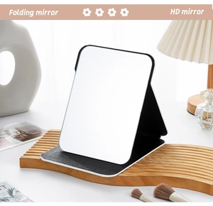 Detailed view of black portable folding makeup mirror on a stylish wooden tray