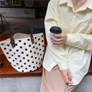 French vintage polka dot canvas tote bag with brown leather handles in outdoor setting