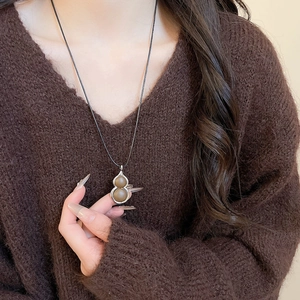 Brown gourd pendant necklace with silver metal frame and black braided cord on model