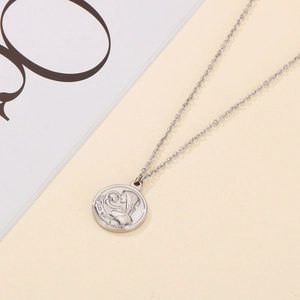 Detail of silver round medallion necklace showing mother and baby relief carving