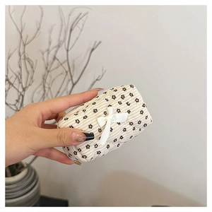 Close-up of mini floral cotton makeup bag with a white bow held in hand