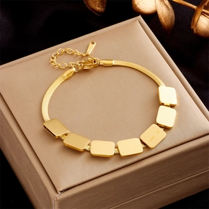 Detail of adjustable gold snake chain bracelet with seven rectangular charms on a jewelry box