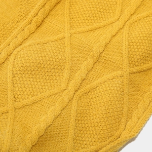 Macro shot of thick ginger yellow cable knit patterns on a warm winter beanie set