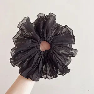 Detailed view of oversized black pleated chiffon scrunchie with layered ruffle texture