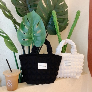 Detailed view of bubble quilted canvas tote bags in black and white with logo patch