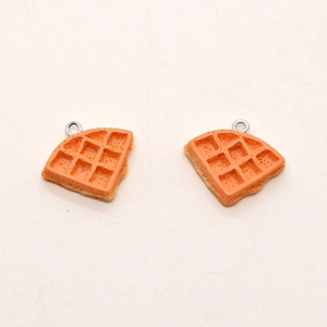 Macro detail of resin waffle charms with realistic texture and metal hanging loops