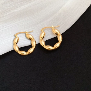 Detail of golden C-shaped hoop earrings featuring linked oval beads and metallic shine